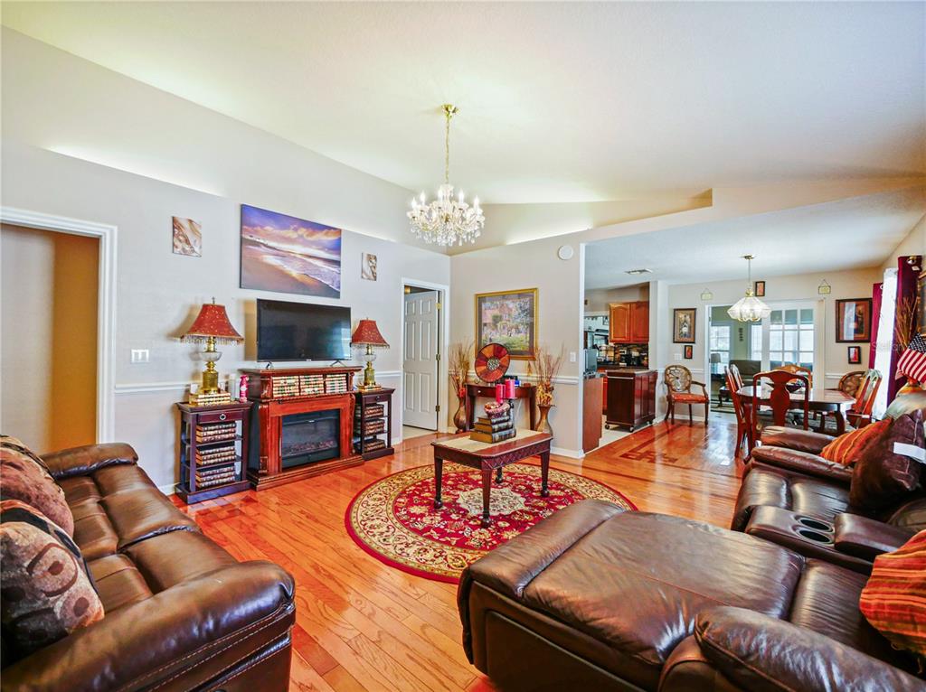 A living room with hardwood floors, a fireplace, a chandelier, and leather furniture — 4856 ROBBINS AVENUE, ORLANDO, FL