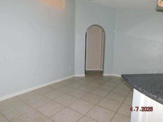 An empty room with light blue walls, tile flooring, and an arched doorway — 1625 SW 43RD STREET, CAPE CORAL, FL