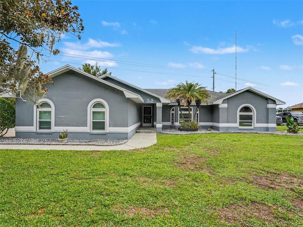 A single-story gray house with white trim, arched windows, and a front walkway — 6736 NELLS WAY, LAKELAND, FL
