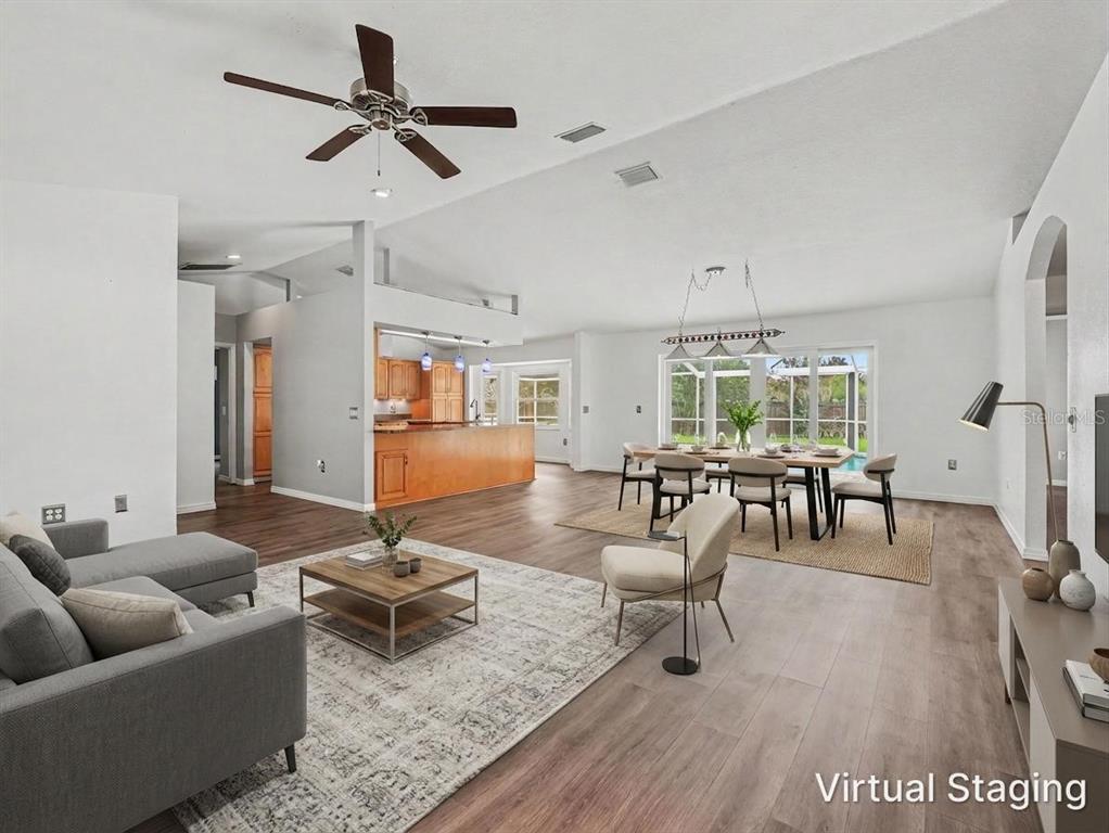 A spacious open-concept living and dining area with wood-look flooring and virtual staging — 6736 NELLS WAY, LAKELAND, FL