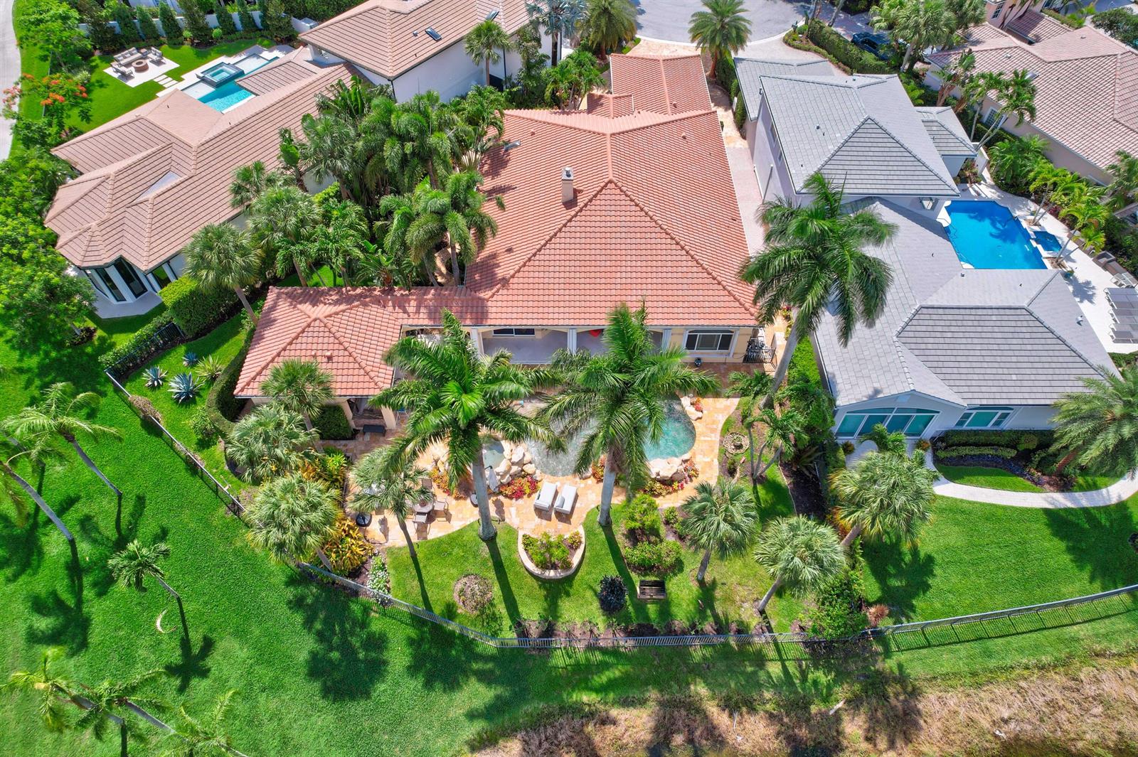 An aerial view shows a house with a terracotta roof, pool, and surrounding palm trees — 186 Golf Village Boulevard, Jupiter FL 33458, JUPITER, FL
