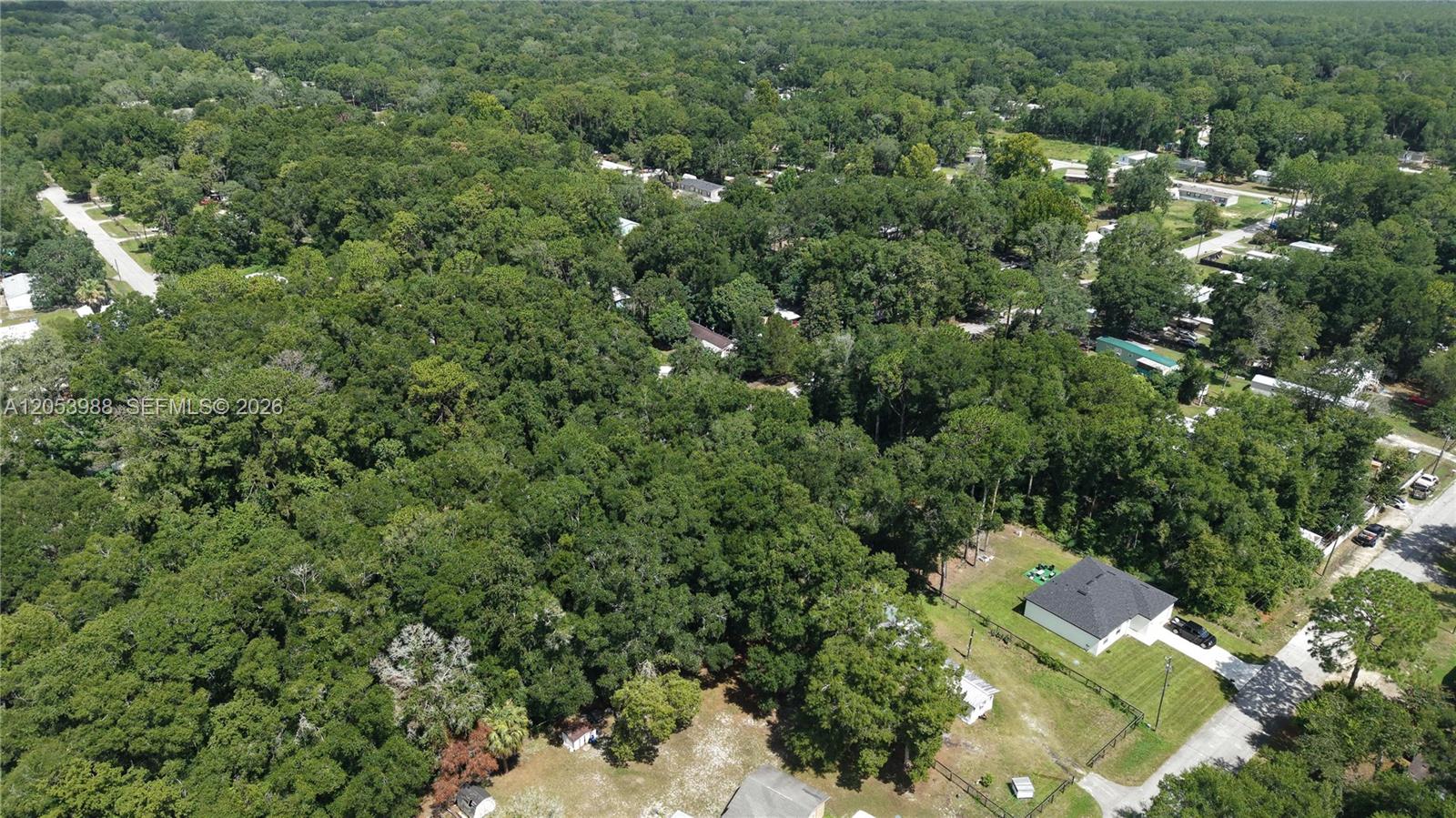 An aerial view shows a house with a dark roof surrounded by dense forest — 0 NW 113th Ave, Ocala FL 34482, OCALA, FL
