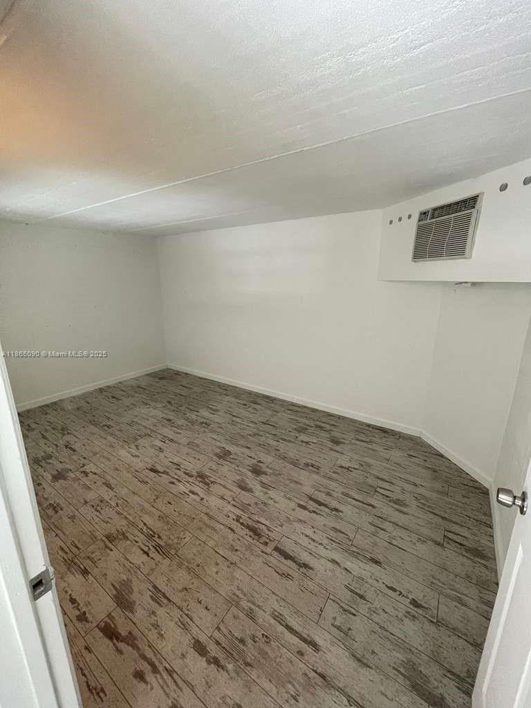 An empty room features white walls, a window air conditioning unit, and wood-look flooring — 1771 Blount Rd # 204, Pompano Beach FL 33069, POMPANO BEACH, FL