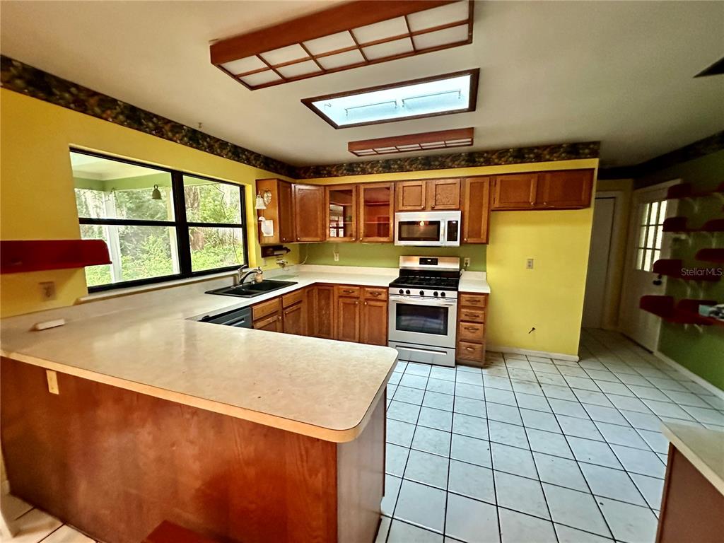 A kitchen with yellow walls, wood cabinets, white countertops, and a tiled floor — 9138 LESWOOD STREET, ORLANDO, FL