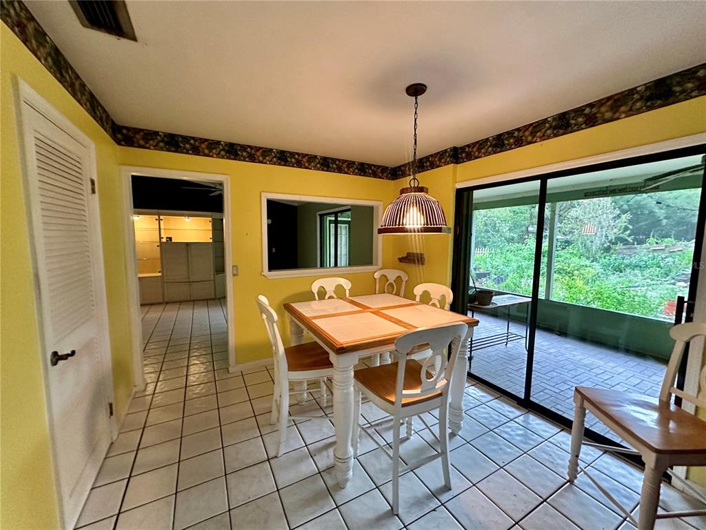 A dining area with yellow walls, tile flooring, a wooden table, and a sliding glass door — 9138 LESWOOD STREET, ORLANDO, FL