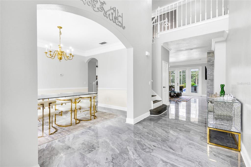 A bright foyer with gray marble floors leads to a dining room and staircase — 8631 TERRACE PINES COURT, ORLANDO, FL