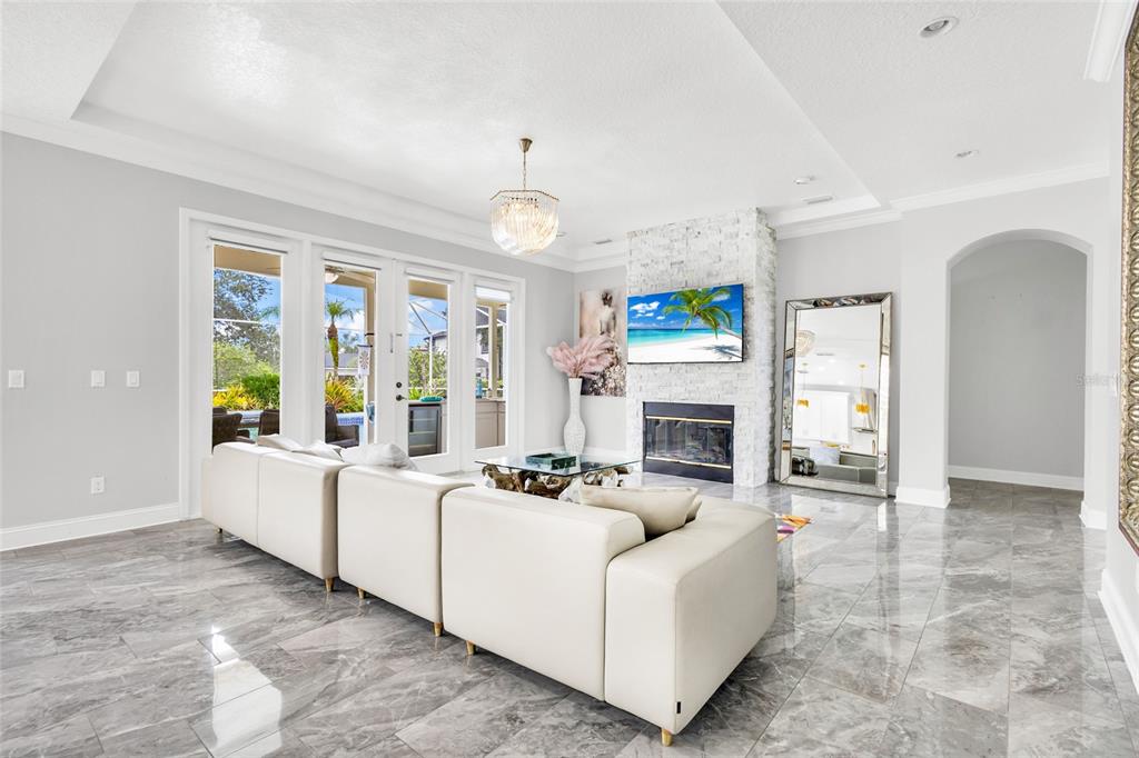 A living room features a white sectional sofa, a stone fireplace, and polished marble floors — 8631 TERRACE PINES COURT, ORLANDO, FL