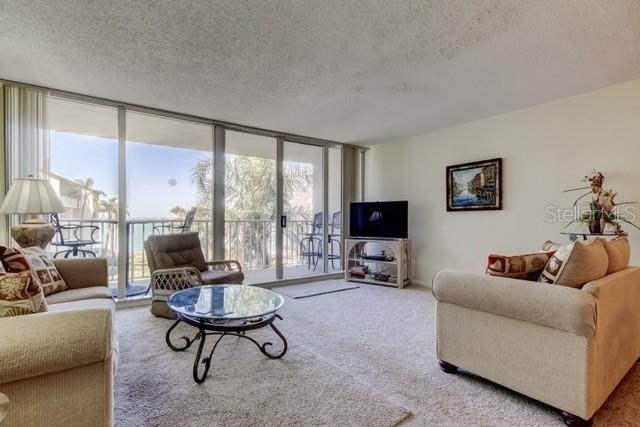 A living room features beige carpet, a glass-topped coffee table, and a balcony with water views — 5155 ISLA KEY BOULEVARD S UNIT 301, ST PETERSBURG, FL