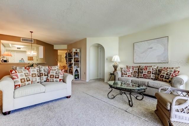A living room features a beige sofa, a glass coffee table, and a wicker chair — 5155 ISLA KEY BOULEVARD S UNIT 301, ST PETERSBURG, FL