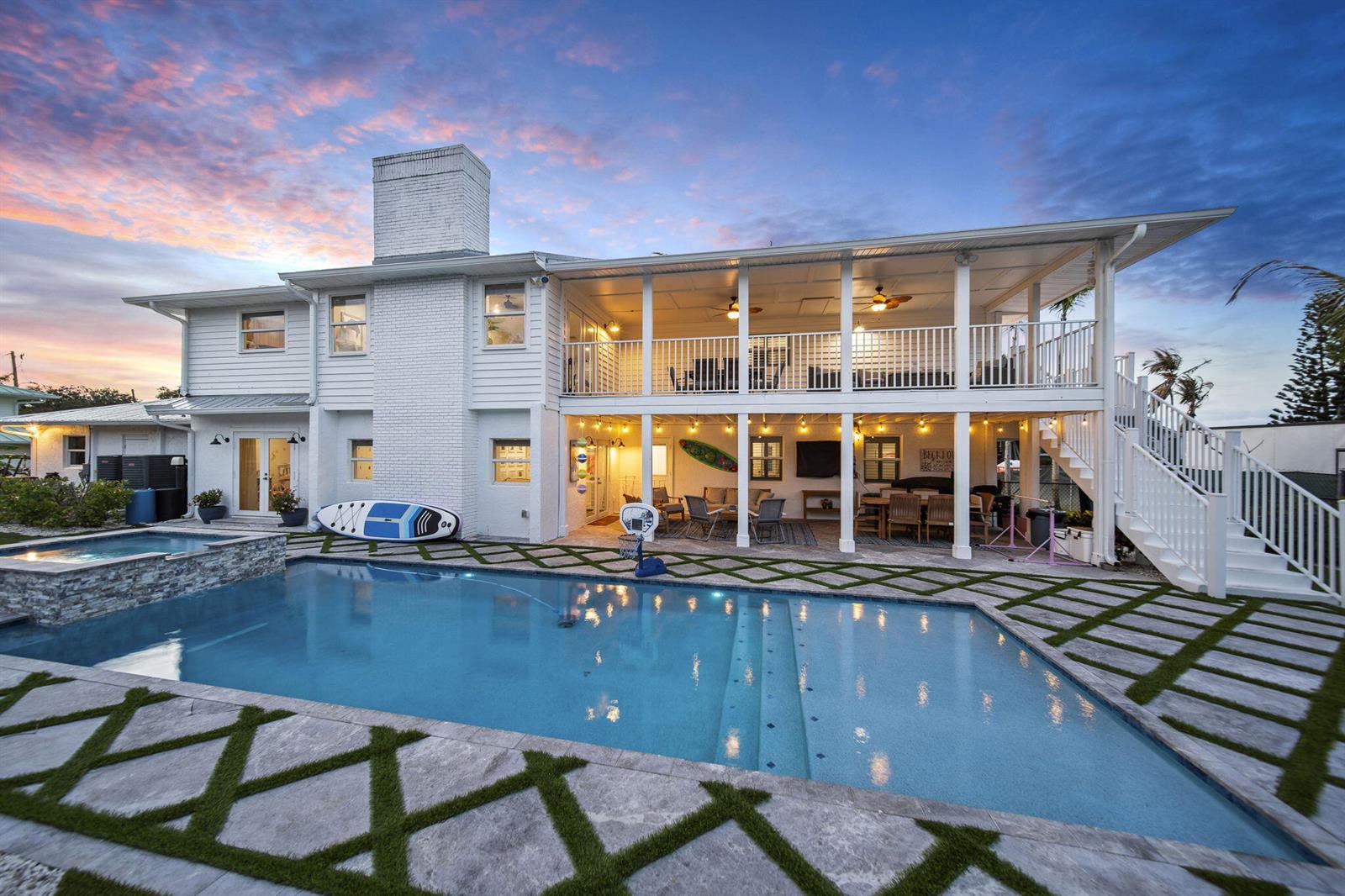 A two-story white house with a pool, covered patio, and balcony at sunset — 473 Peninsula Drive, Fort Pierce FL 34946, FORT PIERCE, FL