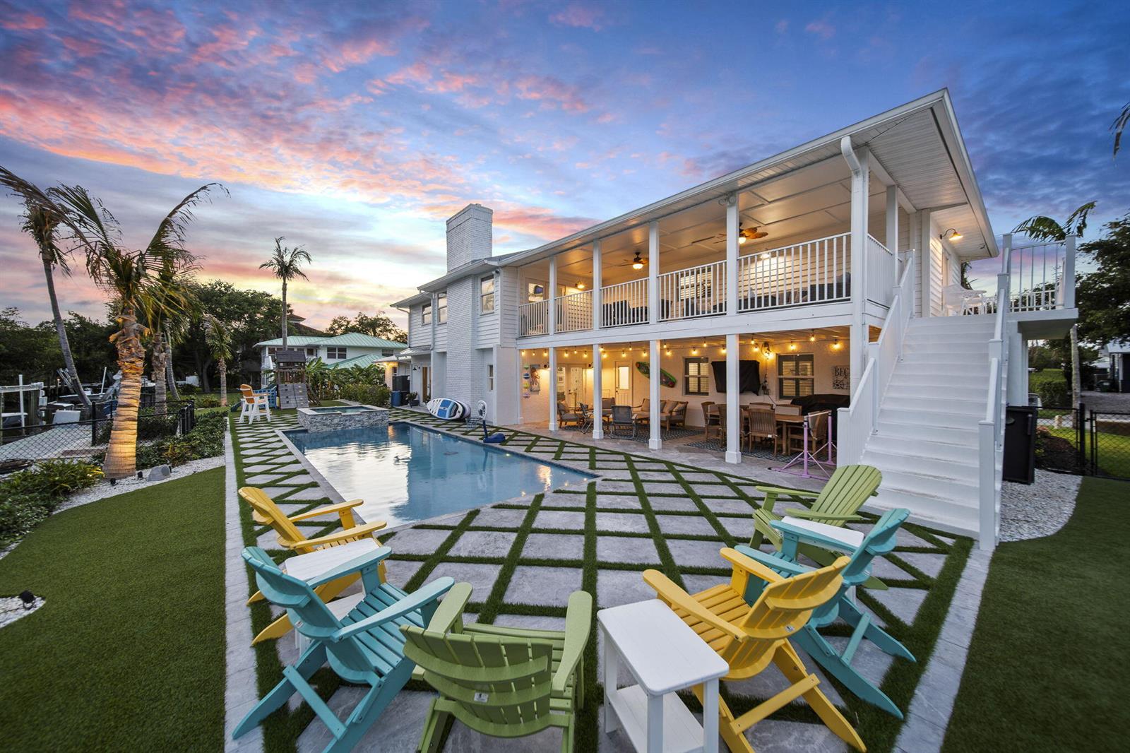 A two-story white house with a pool, patio, and outdoor seating at sunset — 473 Peninsula Drive, Fort Pierce FL 34946, FORT PIERCE, FL