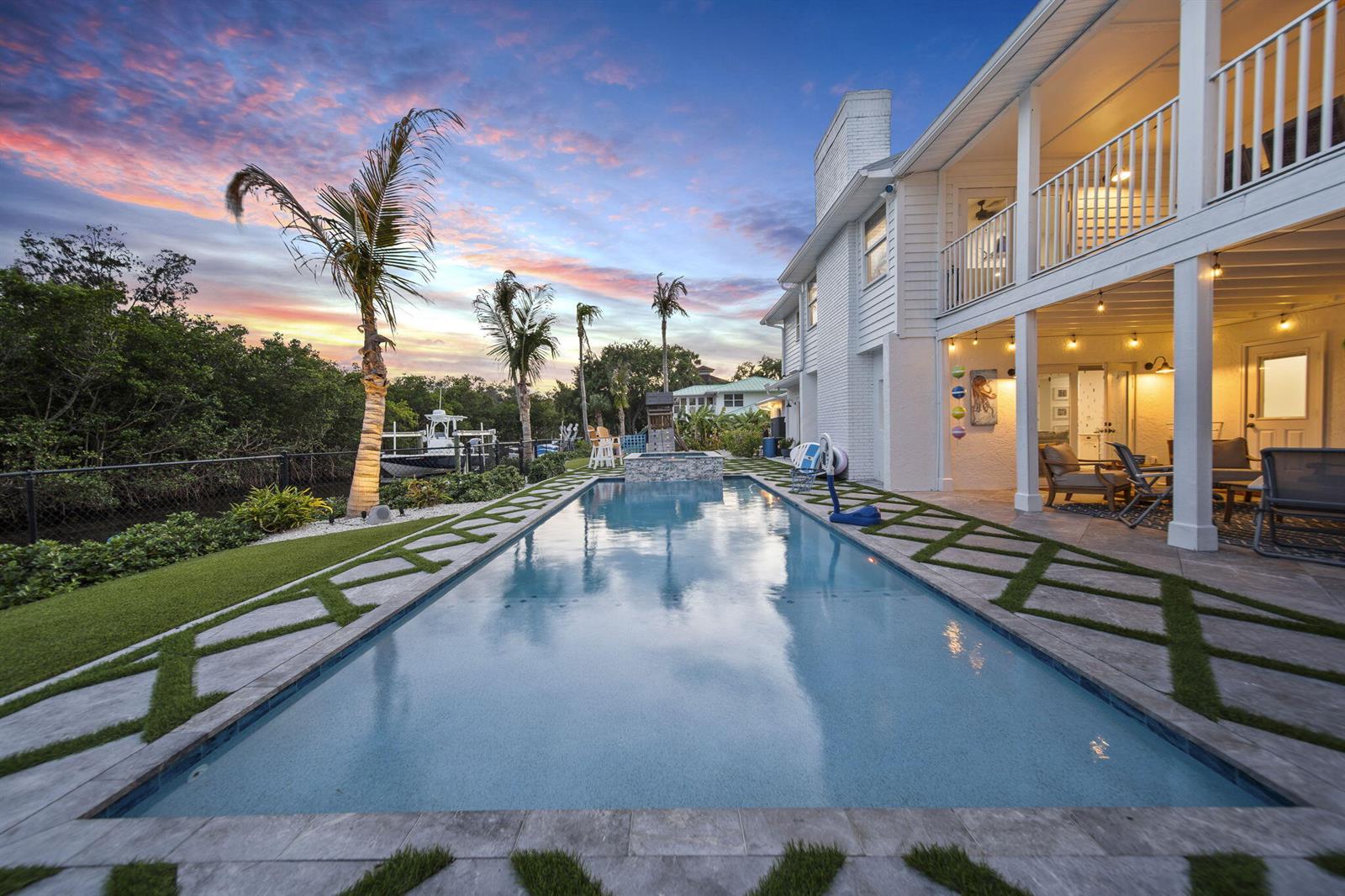 A rectangular swimming pool sits beside a two-story white house with a covered patio — 473 Peninsula Drive, Fort Pierce FL 34946, FORT PIERCE, FL