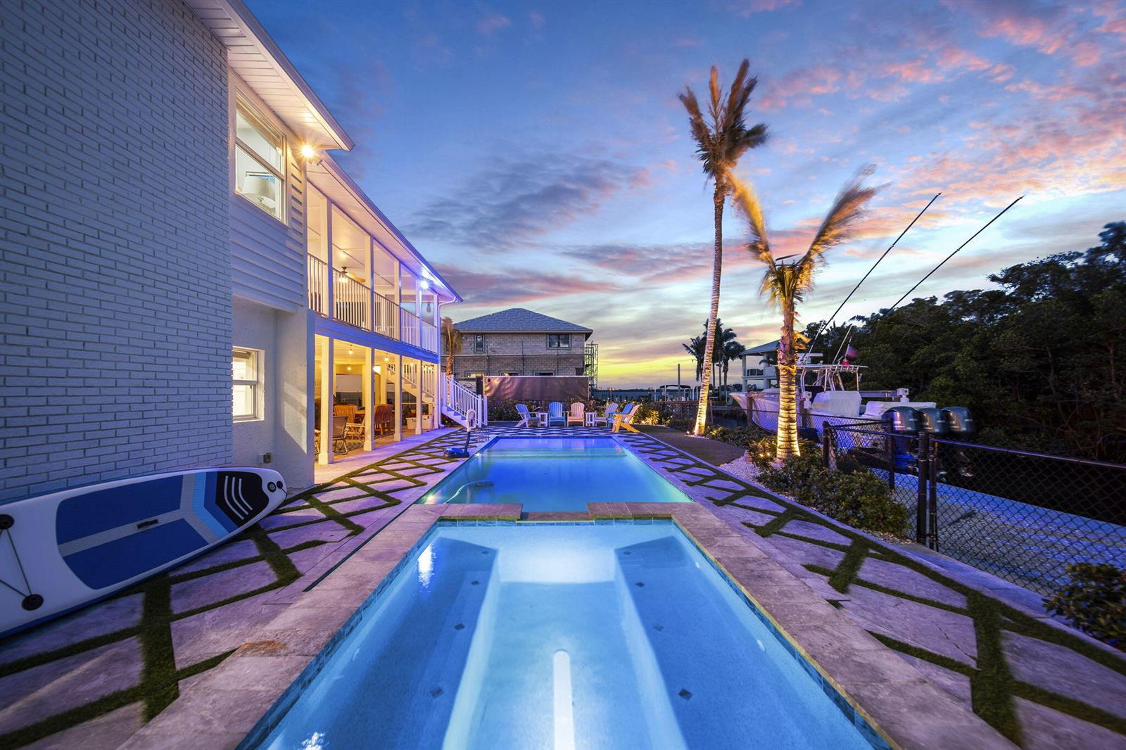 A backyard pool and spa area with a multi-story house and a boat at sunset — 473 Peninsula Drive, Fort Pierce FL 34946, FORT PIERCE, FL