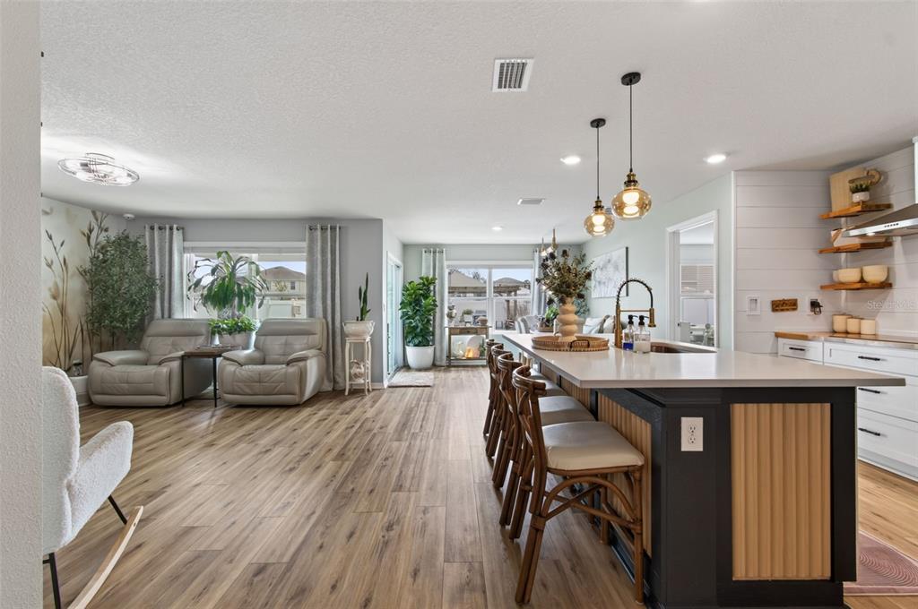 An open-concept kitchen with a dark island and bar seating overlooks a living area — 17077 NW 177TH TERRACE, ALACHUA, FL