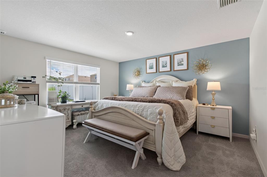 A bedroom features a bed with a bench, a desk, and a blue accent wall — 17077 NW 177TH TERRACE, ALACHUA, FL