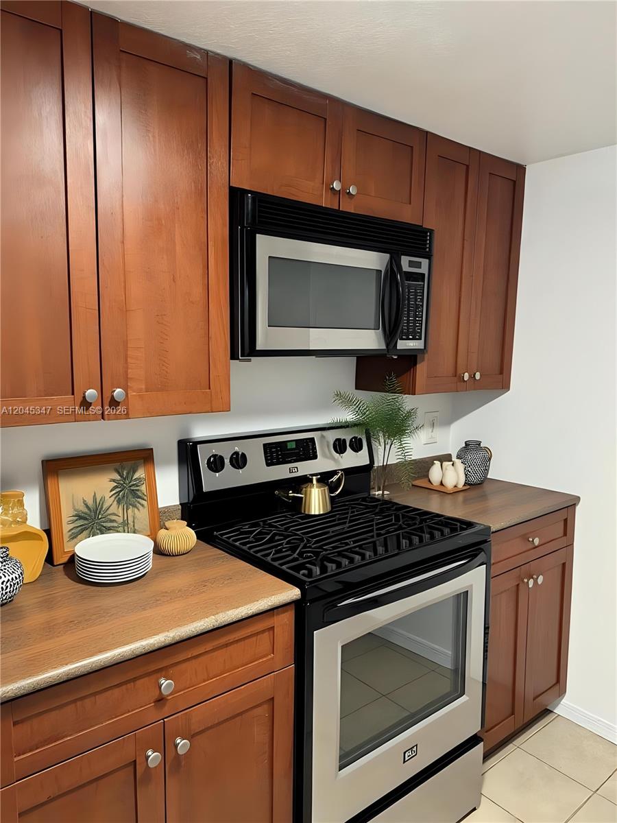 A kitchen features wood cabinets, a stainless steel microwave, and a black electric range — 36 NW 6th Ave # 601, Miami FL 33128, MIAMI, FL