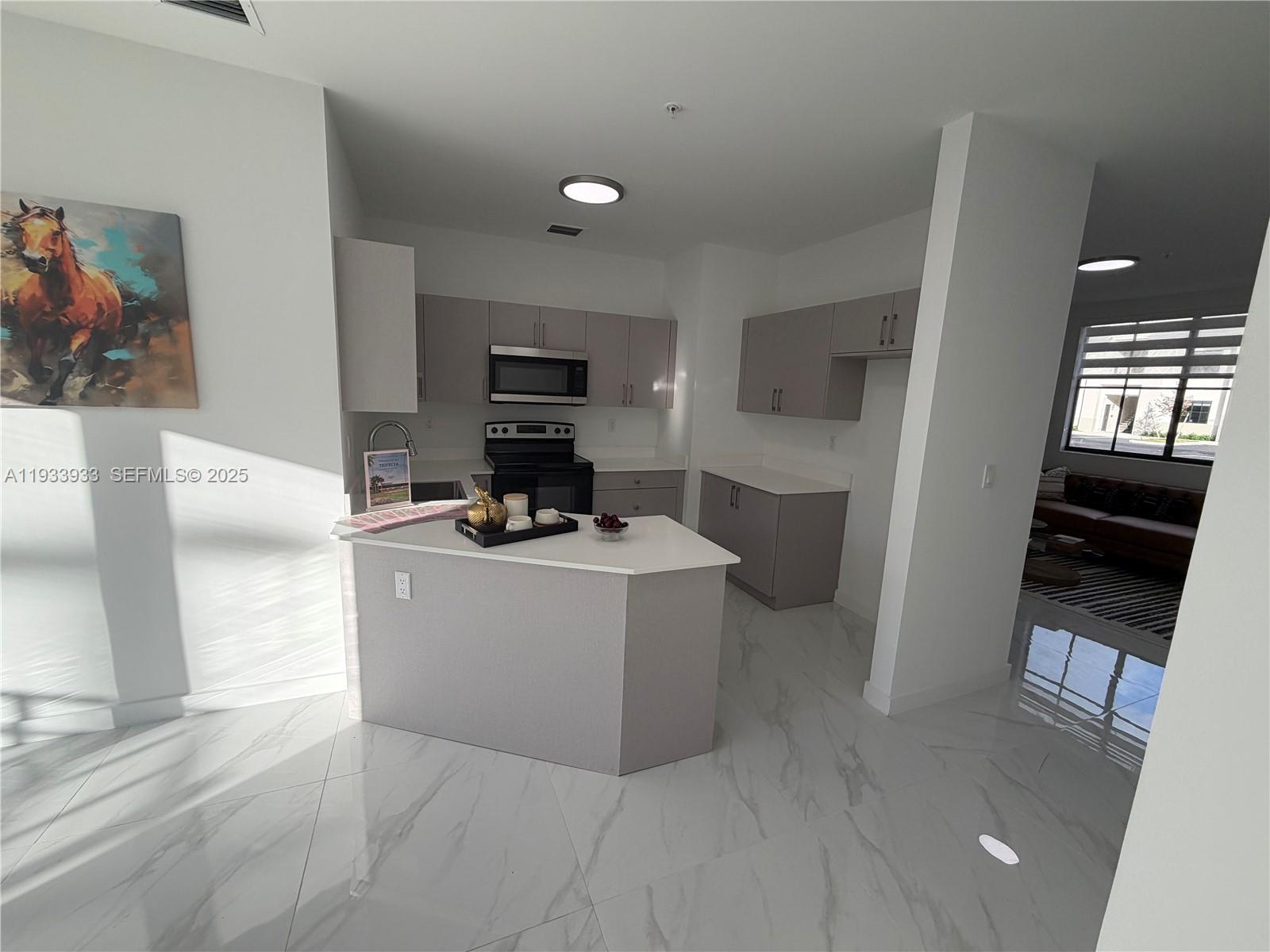A modern kitchen features light gray cabinets, white countertops, and white marble-patterned tile flooring — 2308 E 4th ave # 208, Hialeah FL 33013, HIALEAH, FL