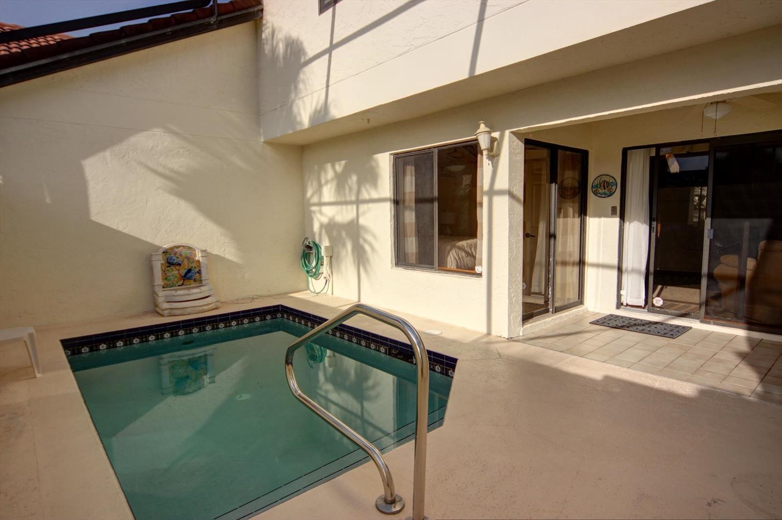 A small rectangular swimming pool sits on a patio next to a house with sliding doors — 508 Sea Oats Drive # 4, Juno Beach FL 33408, JUNO BEACH, FL