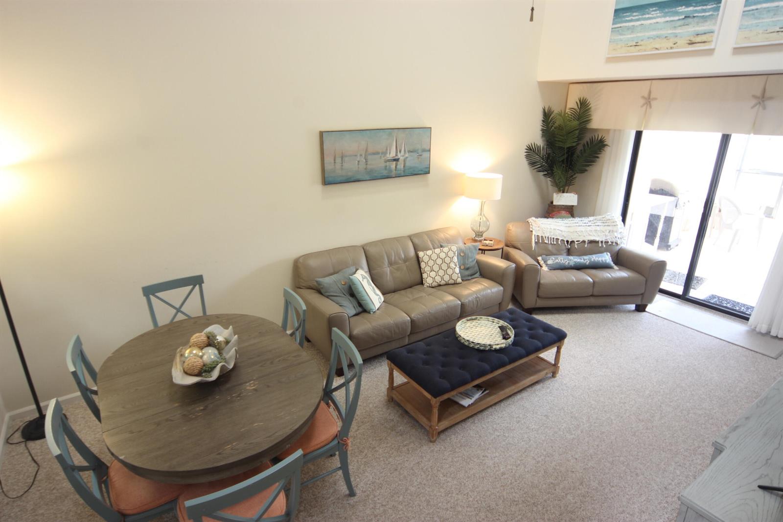 A living and dining area features a round wooden table, leather sofa, and blue ottoman — 508 Sea Oats Drive # 4, Juno Beach FL 33408, JUNO BEACH, FL