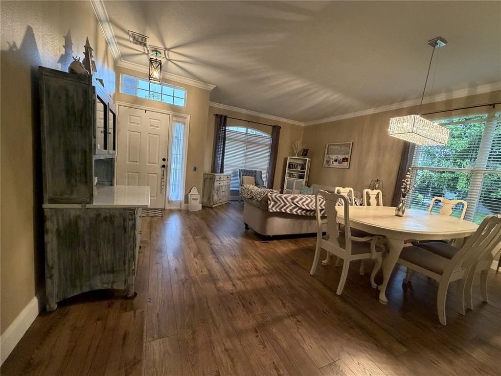 A dining area and living room feature wood-look flooring, neutral walls, and a white hutch — 923 BRIDGEWAY BOULEVARD, ORLANDO, FL