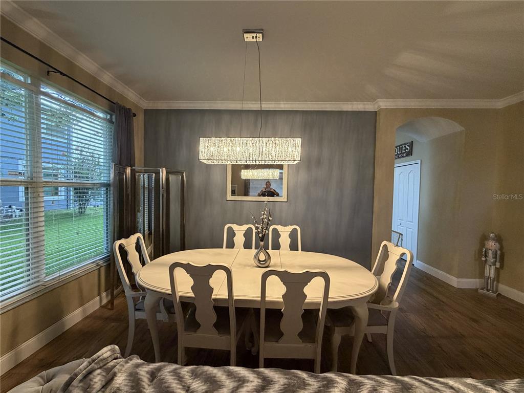 A dining room features a white oval table, six chairs, and a rectangular chandelier — 923 BRIDGEWAY BOULEVARD, ORLANDO, FL