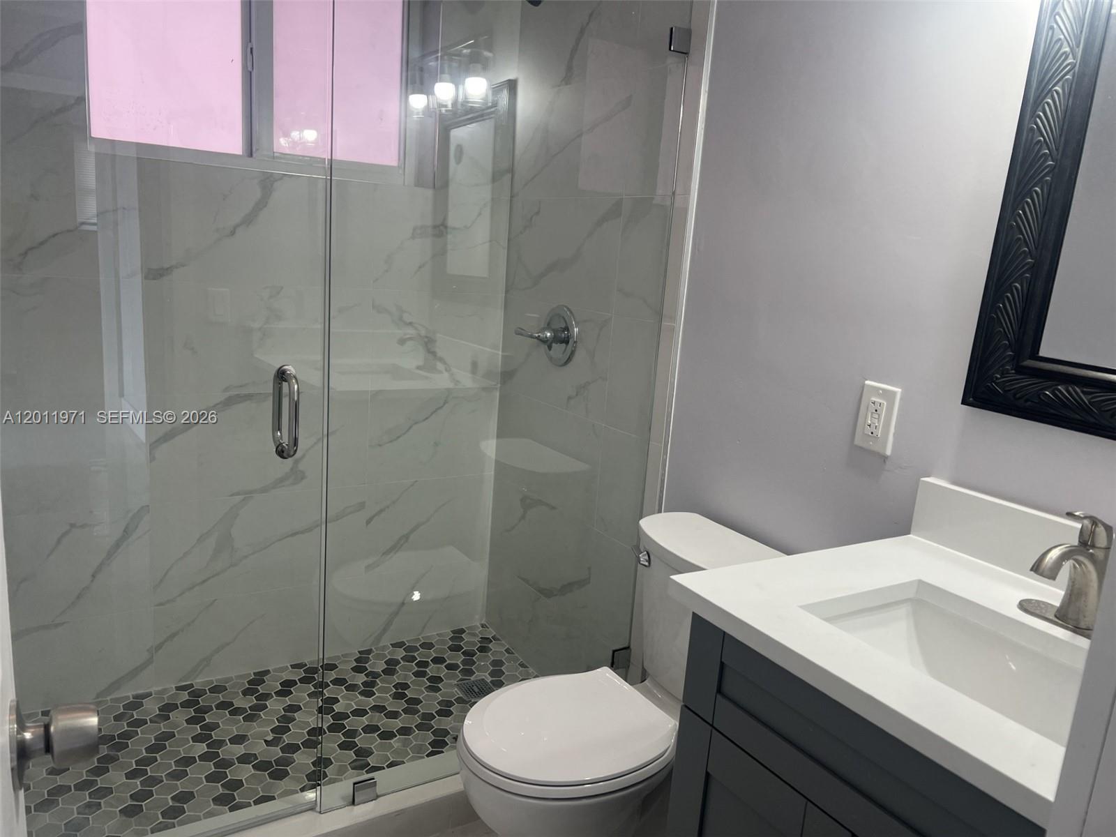 A bathroom features a glass-enclosed shower with marble-look tiles, a toilet, and a vanity — 1067 NW 24th St # 1067, Miami FL 33127, MIAMI, FL
