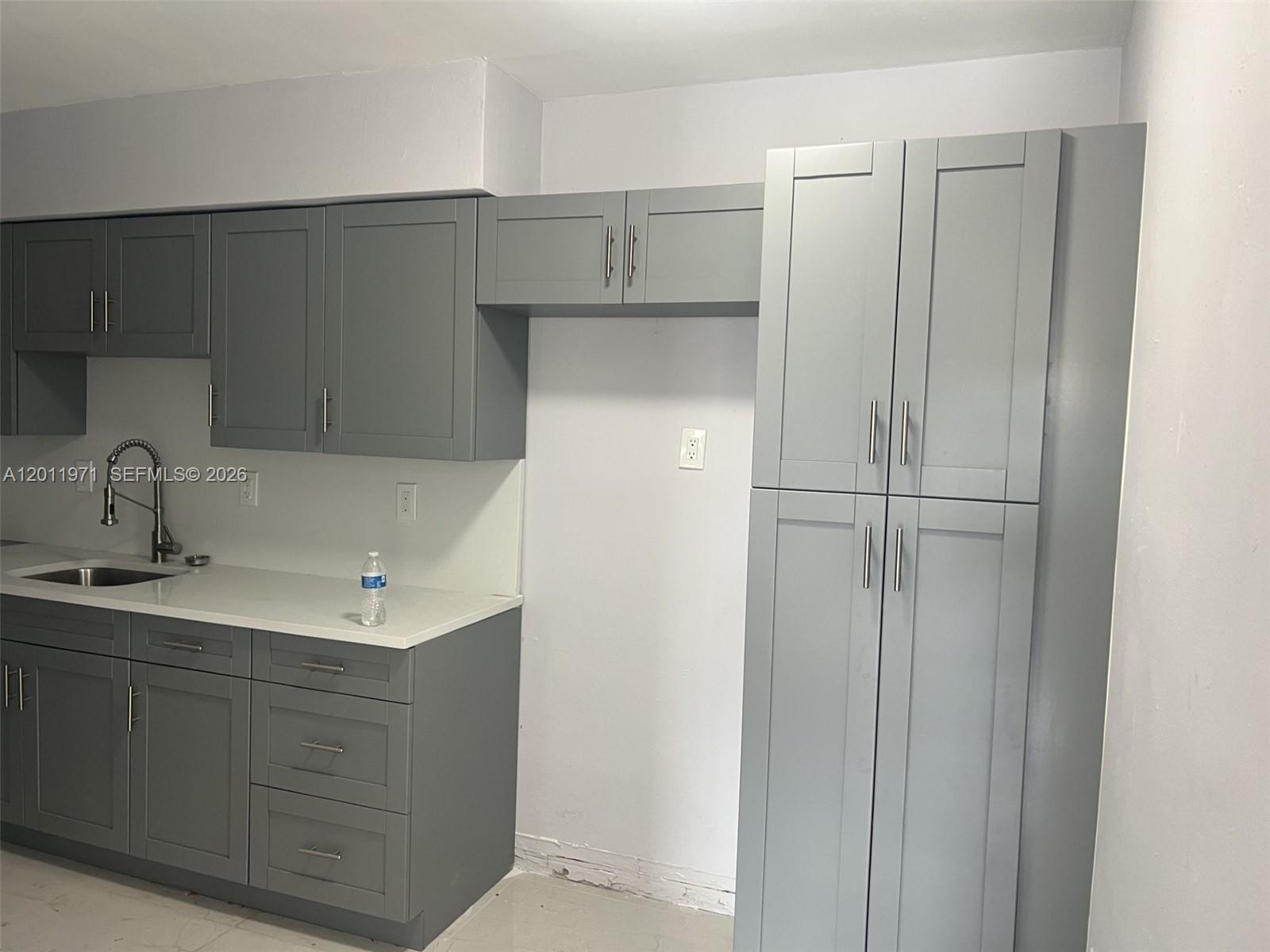 A kitchen features grey shaker-style cabinets, white countertops, and a stainless steel faucet — 1067 NW 24th St # 1067, Miami FL 33127, MIAMI, FL