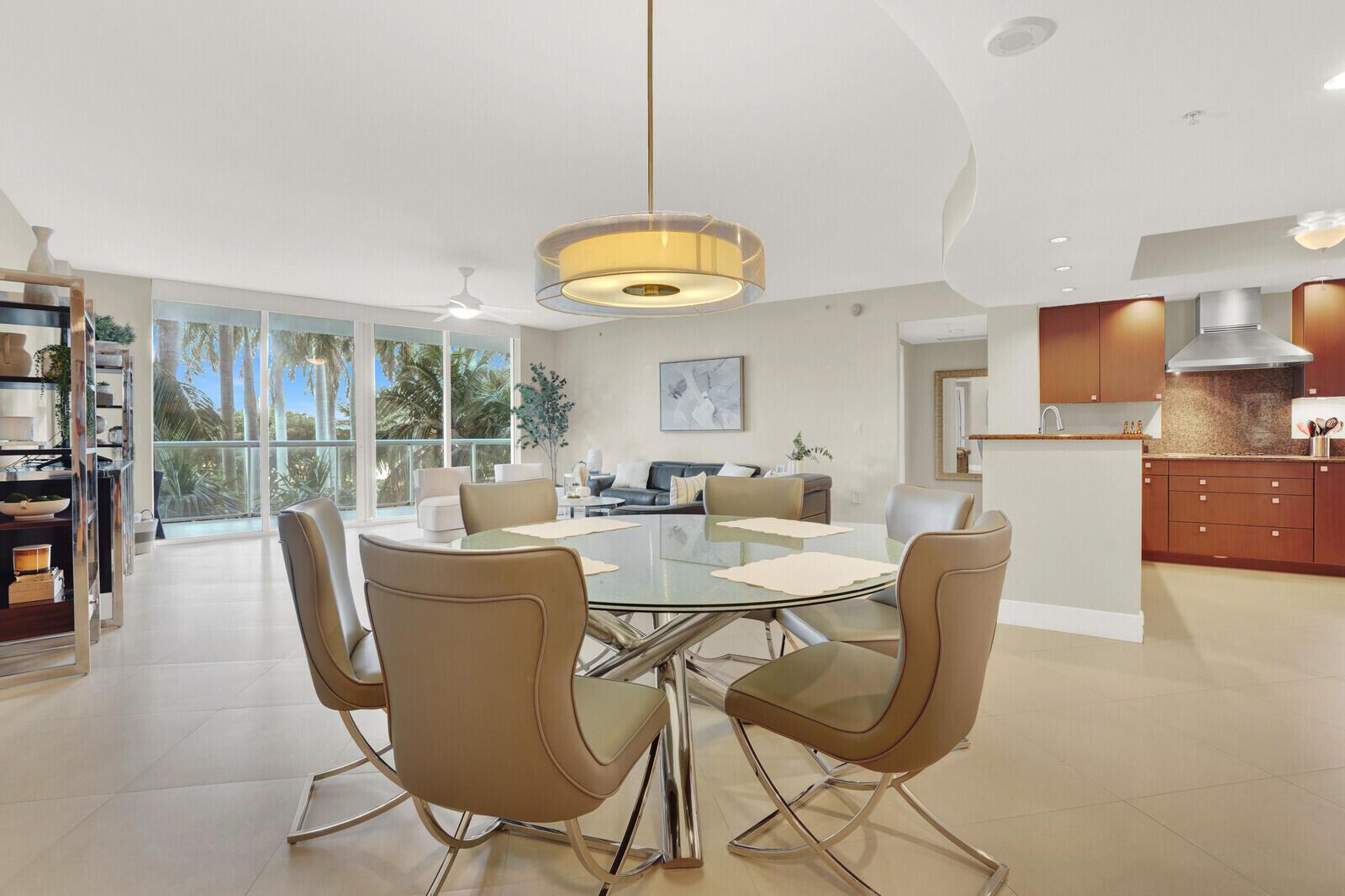 A dining area with a glass table and chairs sits before an open kitchen and balcony — 1 N Ocean Boulevard # 508, Pompano Beach FL 33062, POMPANO BEACH, FL