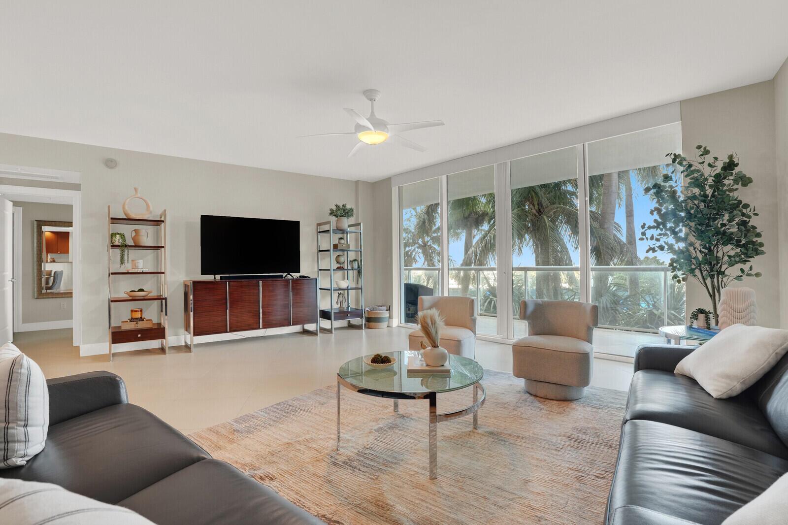 A living room features a dark wood media console, two gray armchairs, and floor-to-ceiling windows — 1 N Ocean Boulevard # 508, Pompano Beach FL 33062, POMPANO BEACH, FL