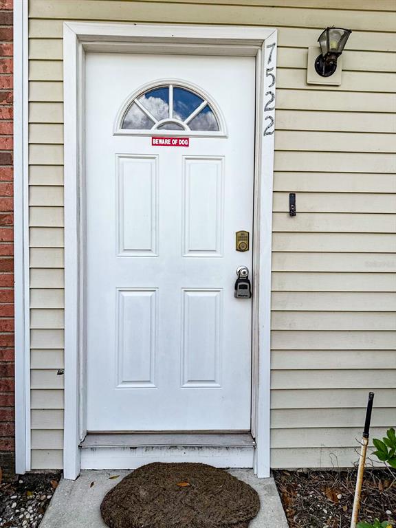 A white front door with a small arched window and a beware of dog sign — 7522 HOLLOWELL DRIVE, TAMPA, FL