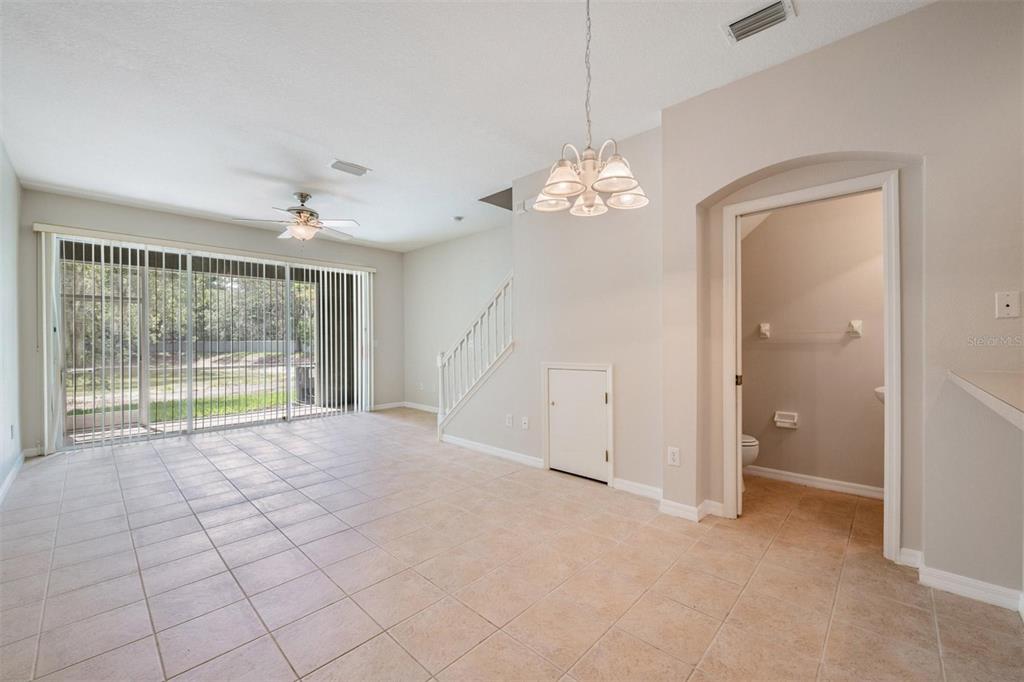 A tiled dining area features a chandelier, a staircase, and an adjacent half bathroom — 2461 EARLSWOOD COURT, BRANDON, FL
