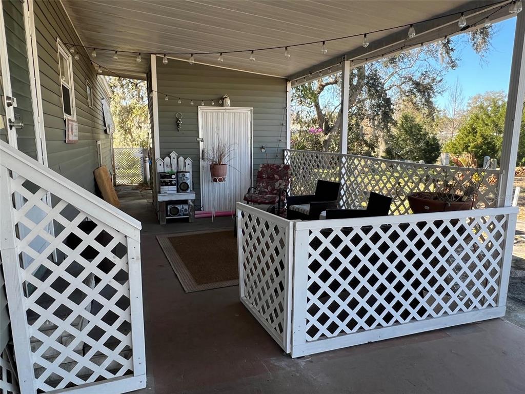 A covered porch features white lattice railings, outdoor seating, and string lights — 29250 US HIGHWAY 19 N UNIT 300, CLEARWATER, FL