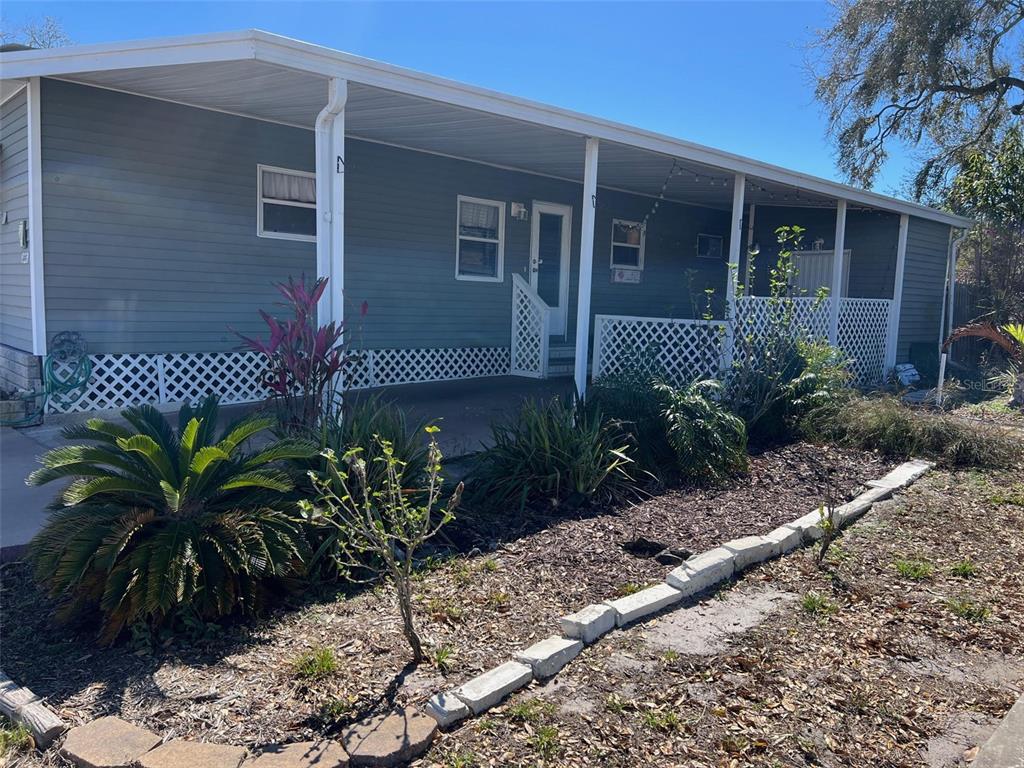 A single-story house with a covered porch, lattice skirting, and a landscaped front yard — 29250 US HIGHWAY 19 N UNIT 300, CLEARWATER, FL