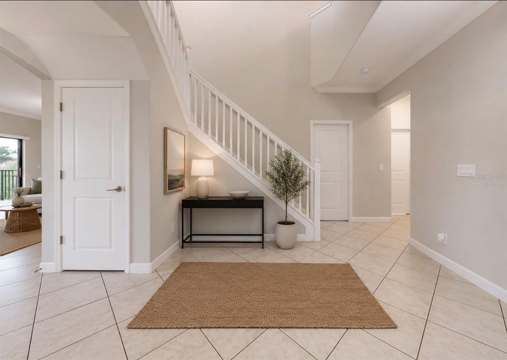 A bright entryway features a staircase, tile flooring, a console table, and neutral wall paint — 9924 SMARTY JONES DRIVE, RUSKIN, FL