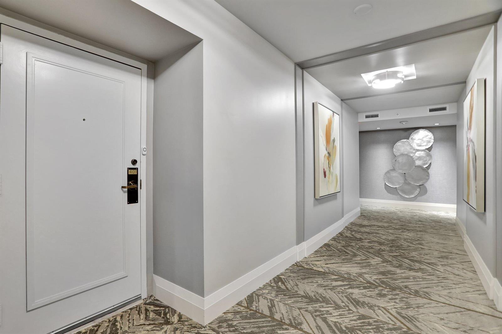 A hotel hallway features a white door, patterned carpet, wall art, and a decorative metal sculpture — 4748 S Ocean Boulevard # 301, Highland Beach FL 33487, HIGHLAND BEACH, FL