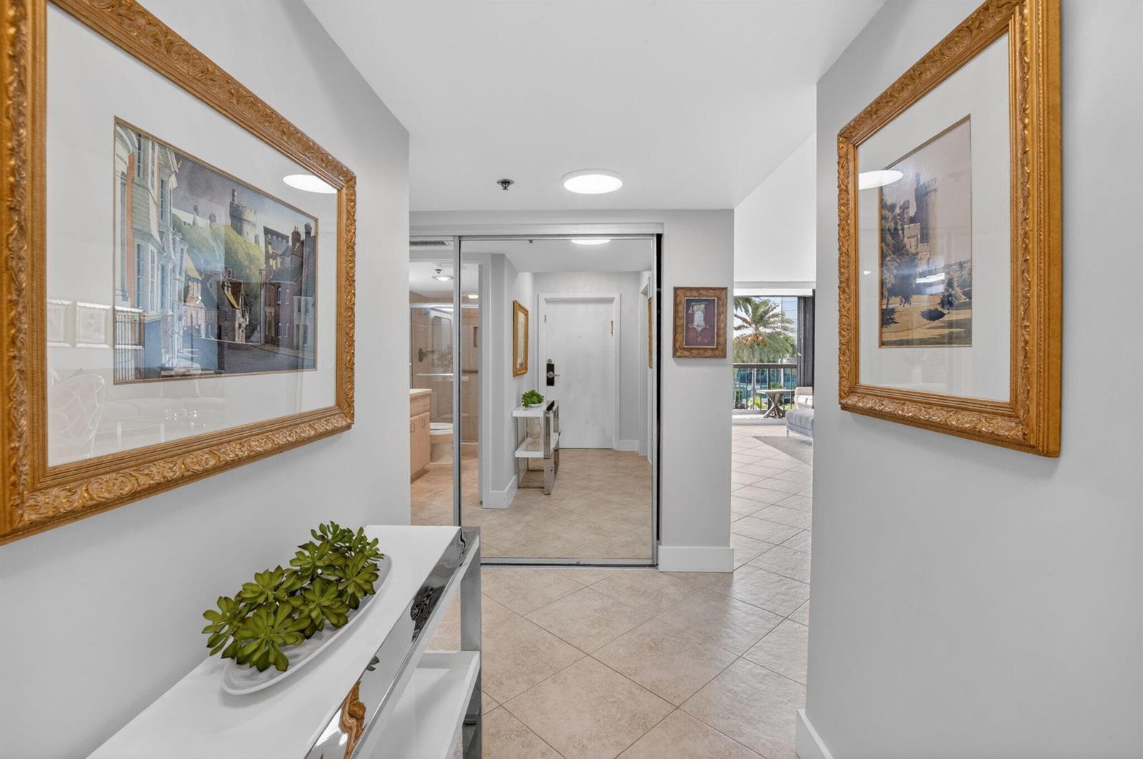 A tiled hallway features a mirrored closet, a console table with greenery, and framed artwork — 4748 S Ocean Boulevard # 301, Highland Beach FL 33487, HIGHLAND BEACH, FL