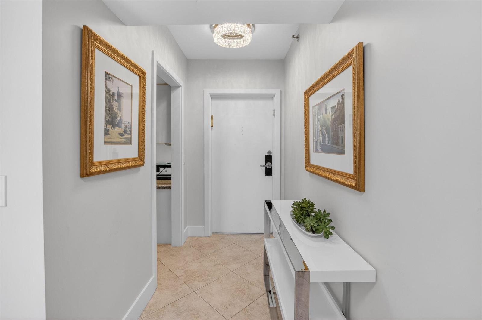 A bright entryway features a white console table, framed artwork, and tile flooring — 4748 S Ocean Boulevard # 301, Highland Beach FL 33487, HIGHLAND BEACH, FL