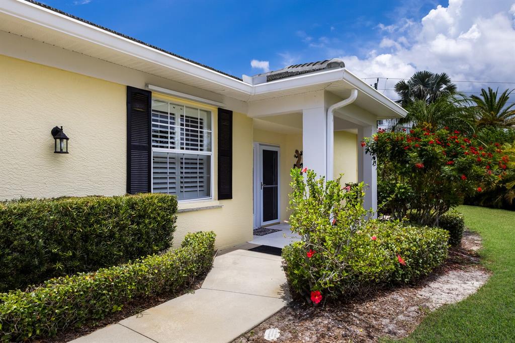 A yellow house exterior features a concrete walkway leading to a covered front entryway — 915 SW BARCLAY COURT, VENICE, FL