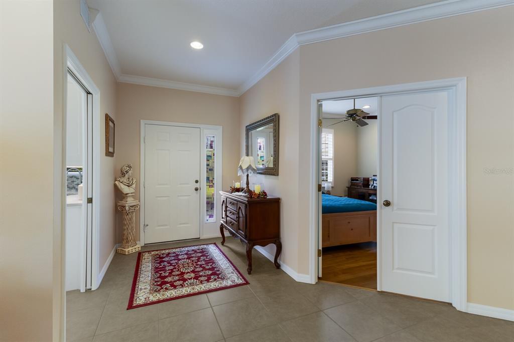 A tiled entryway features a front door with a sidelight, a console table, and a rug — 915 SW BARCLAY COURT, VENICE, FL