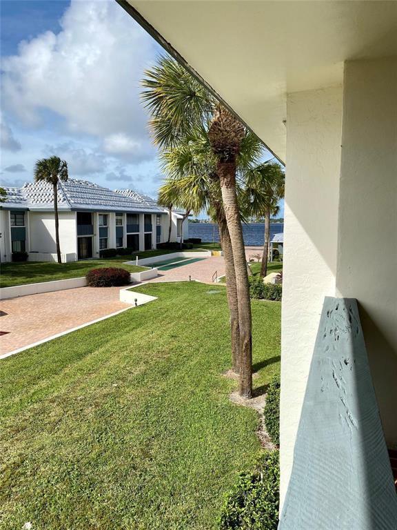 A view from a balcony overlooking a lawn, palm trees, and a waterfront building — 175 SE Saint Lucie Boulevard # C34, Stuart FL 34996, STUART, FL