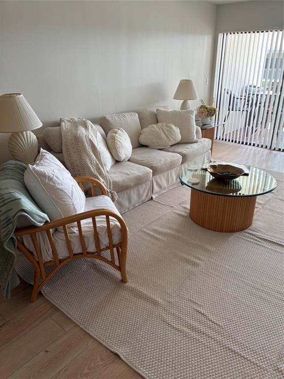 A living room features a beige sofa, a rattan armchair, and a glass-topped coffee table — 175 SE Saint Lucie Boulevard # C34, Stuart FL 34996, STUART, FL