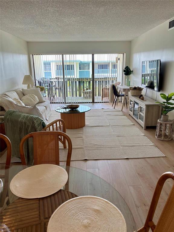 A living room features light wood flooring, a large area rug, and a glass sliding door — 175 SE Saint Lucie Boulevard # C34, Stuart FL 34996, STUART, FL