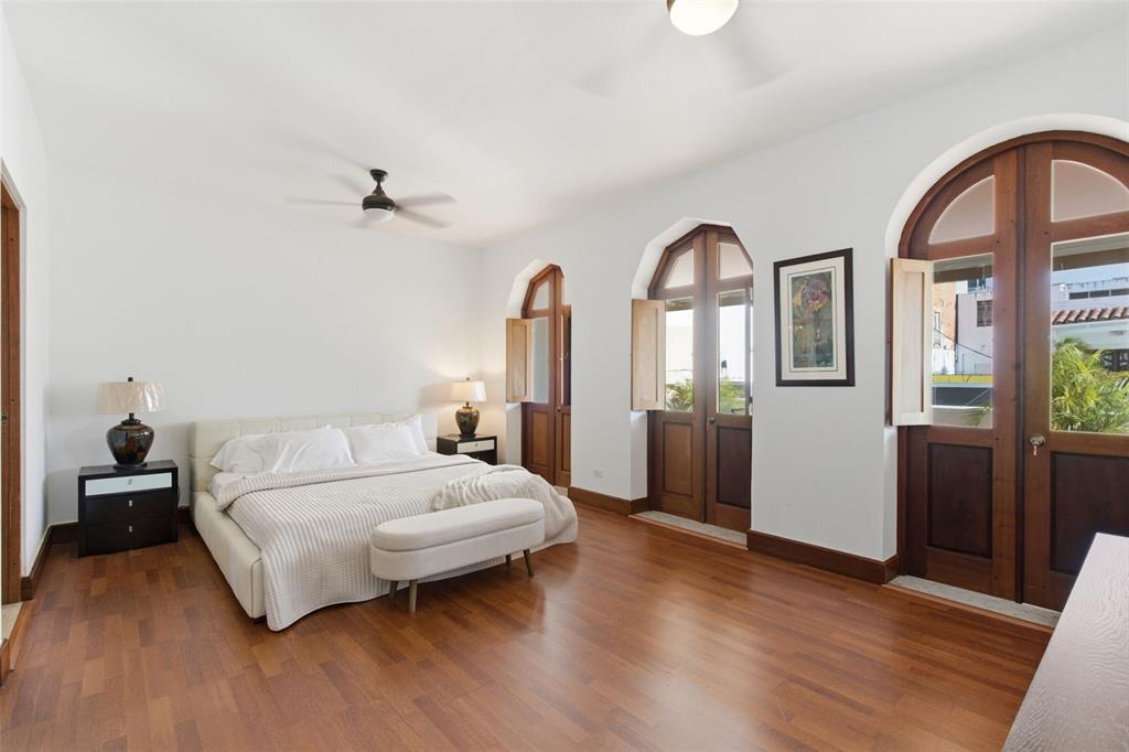 A bedroom features a bed, wooden floors, and arched glass doors opening to a balcony — 65 CALLE SAN FRANCISCO, OLD SAN JUAN, PR