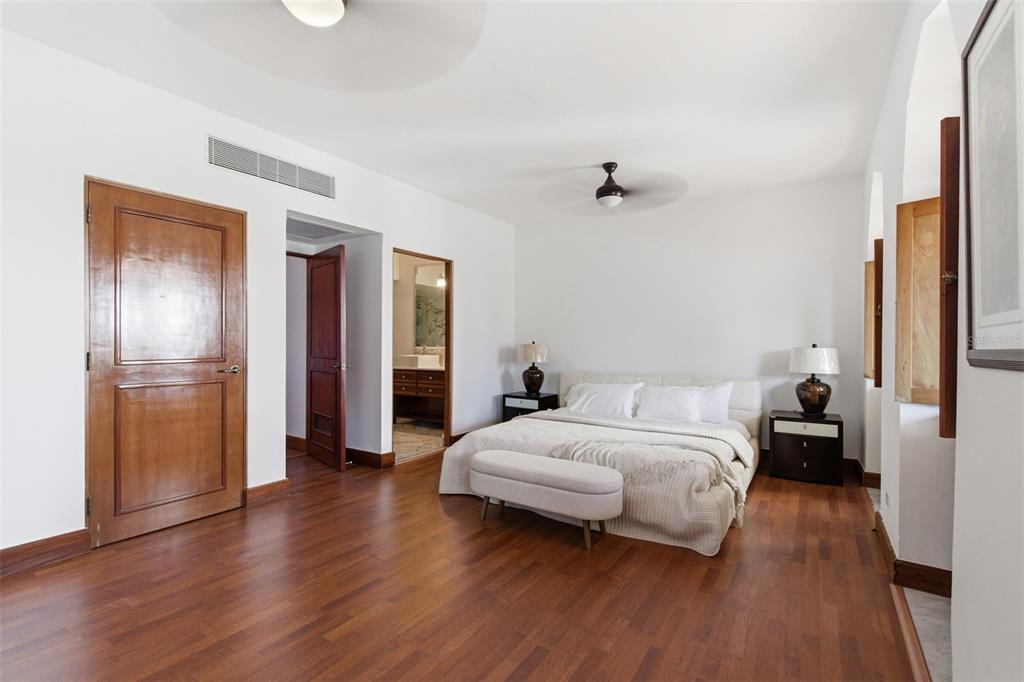 A bedroom features hardwood floors, a white bed with a bench, and two wooden doors — 65 CALLE SAN FRANCISCO, OLD SAN JUAN, PR