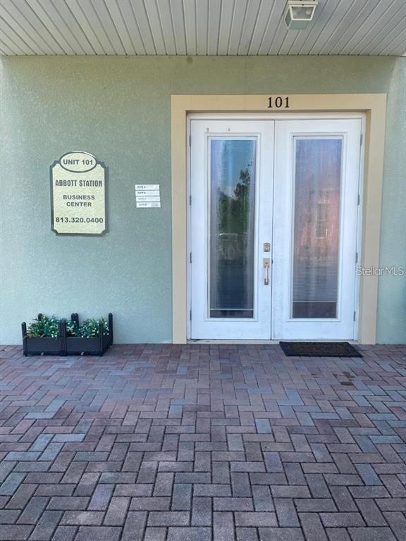 The exterior entrance to a business unit features double glass doors and a brick patio — 6272 ABBOTT STATION DRIVE UNIT 101-20, ZEPHYRHILLS, FL