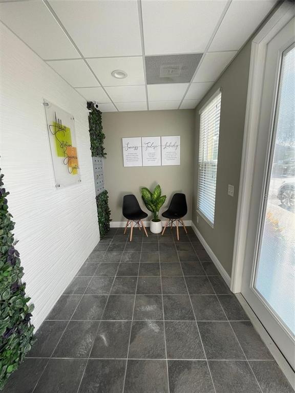 A small waiting area features dark tile flooring, two black chairs, and a potted plant — 6272 ABBOTT STATION DRIVE UNIT 101-20, ZEPHYRHILLS, FL