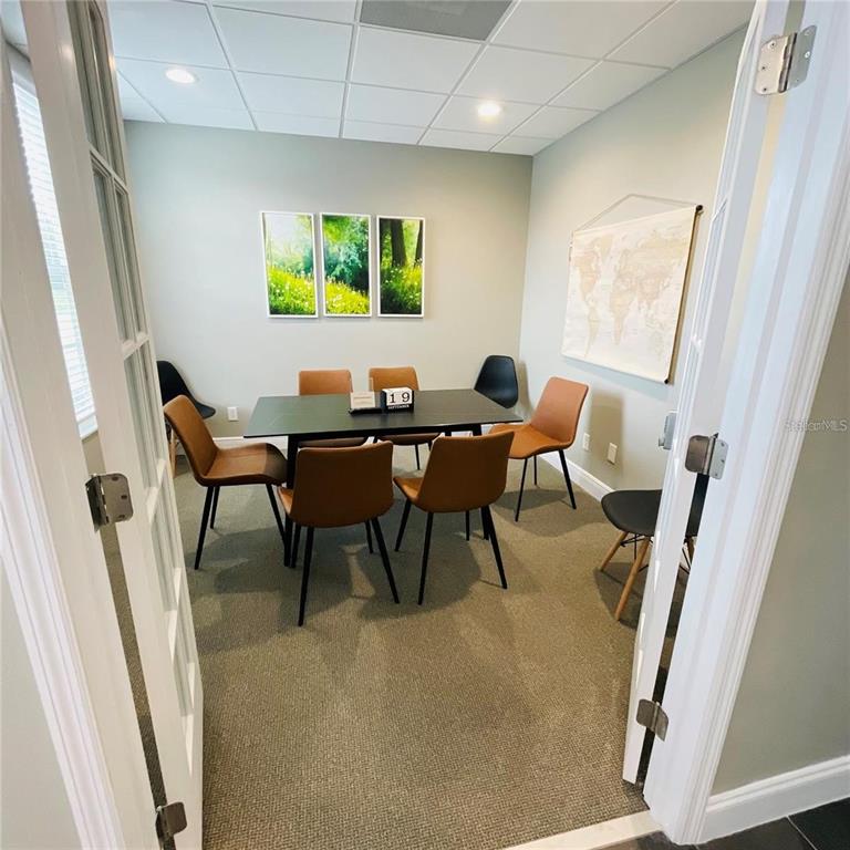 A small conference room features a black table, tan chairs, and a wall-mounted world map — 6272 ABBOTT STATION DRIVE UNIT 101-20, ZEPHYRHILLS, FL