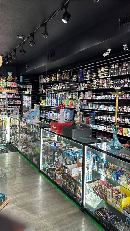 A retail shop features glass display cases, wall-mounted shelving, and track lighting on a black ceiling — 0000 WEST LINEBAUGH AVENUE, TAMPA, FL