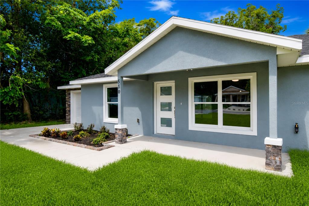 A gray house exterior features a white front door, large windows, and a stone-accented porch — 510 SW 15 AVENUE, OCALA, FL