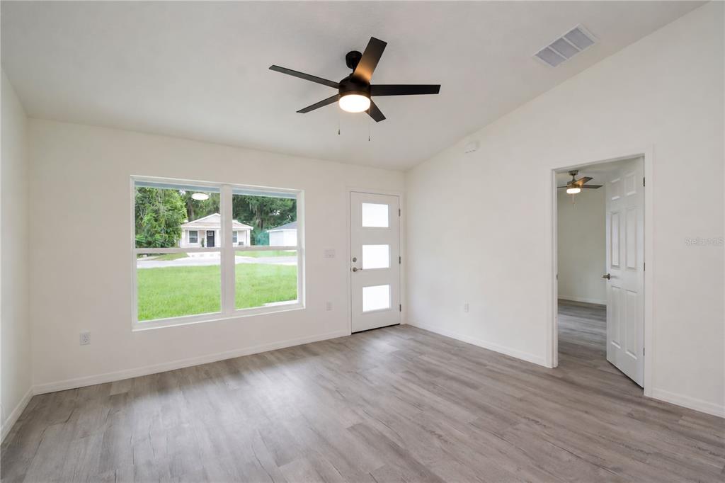 A bright room with white walls, wood-look flooring, a ceiling fan, and a front door — 510 SW 15 AVENUE, OCALA, FL